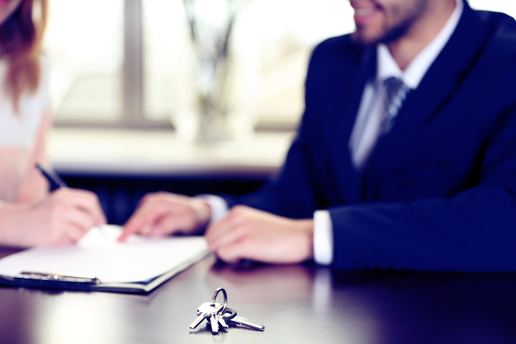 Two individuals in a meeting, with a focus on a set of keys on the table, indicating a possible transaction or agreement.