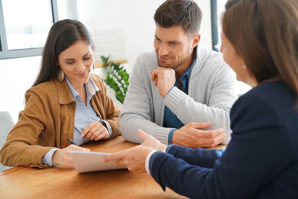 Two people attentively listening and taking notes during a consultation with another individual.